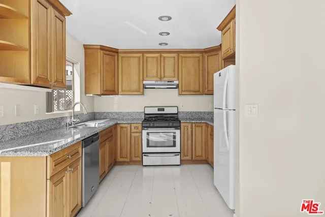 a kitchen with granite countertop a refrigerator and a sink