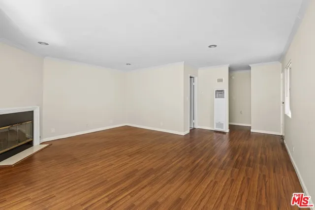 a view of empty room with wooden floor and fireplace