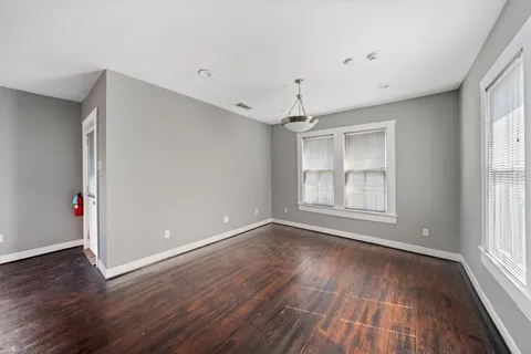 an empty room with wooden floor and windows