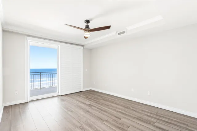 an empty room with wooden floor ceiling fan and window