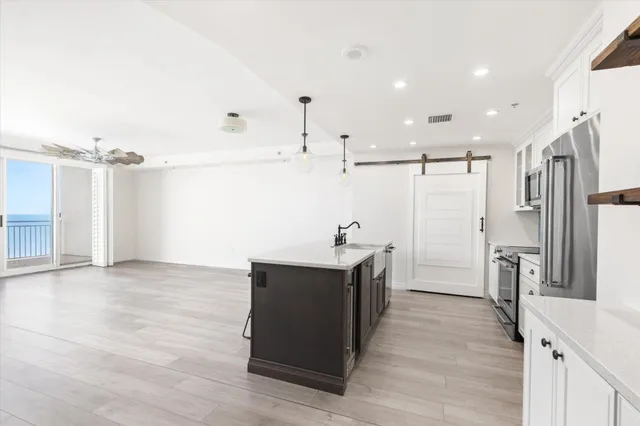 a kitchen with stainless steel appliances kitchen island granite countertop a refrigerator and a sink