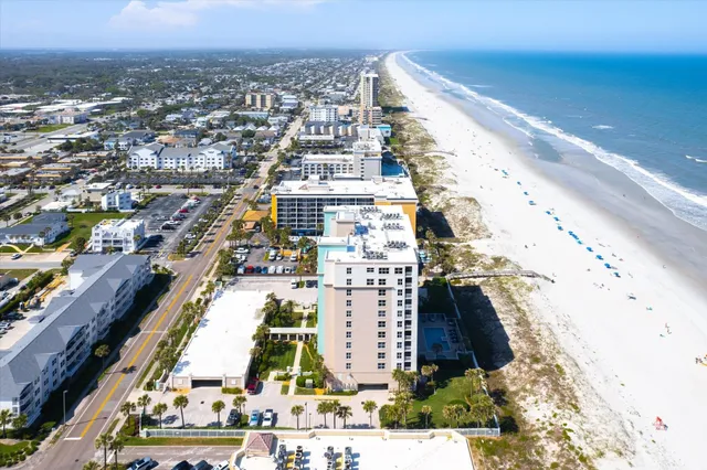 a front view of a residential apartment building with a yard and potted plants