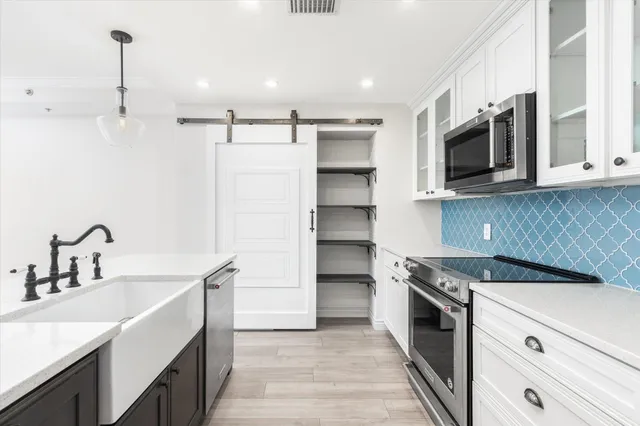 a kitchen with stainless steel appliances white cabinets a sink and a stove