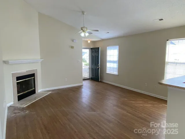an empty room with wooden floor fireplace and windows