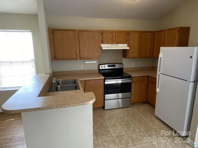 a kitchen with granite countertop a refrigerator stove top oven and sink