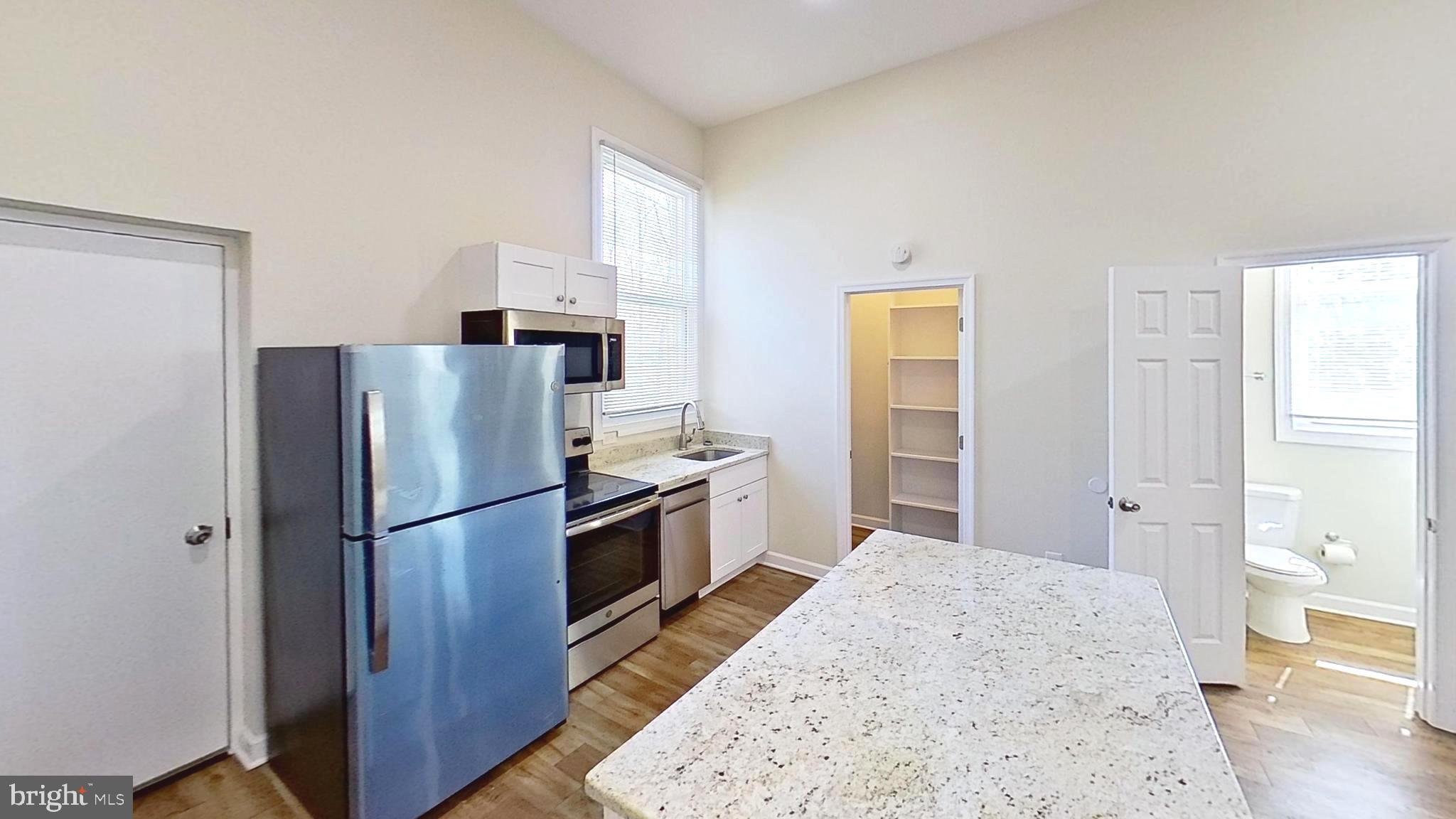 3842 Stoneybrook Road, Unit B White Plains, MD 20695 - Photo 22 of 23 a kitchen with a refrigerator a stove top oven and wooden floor