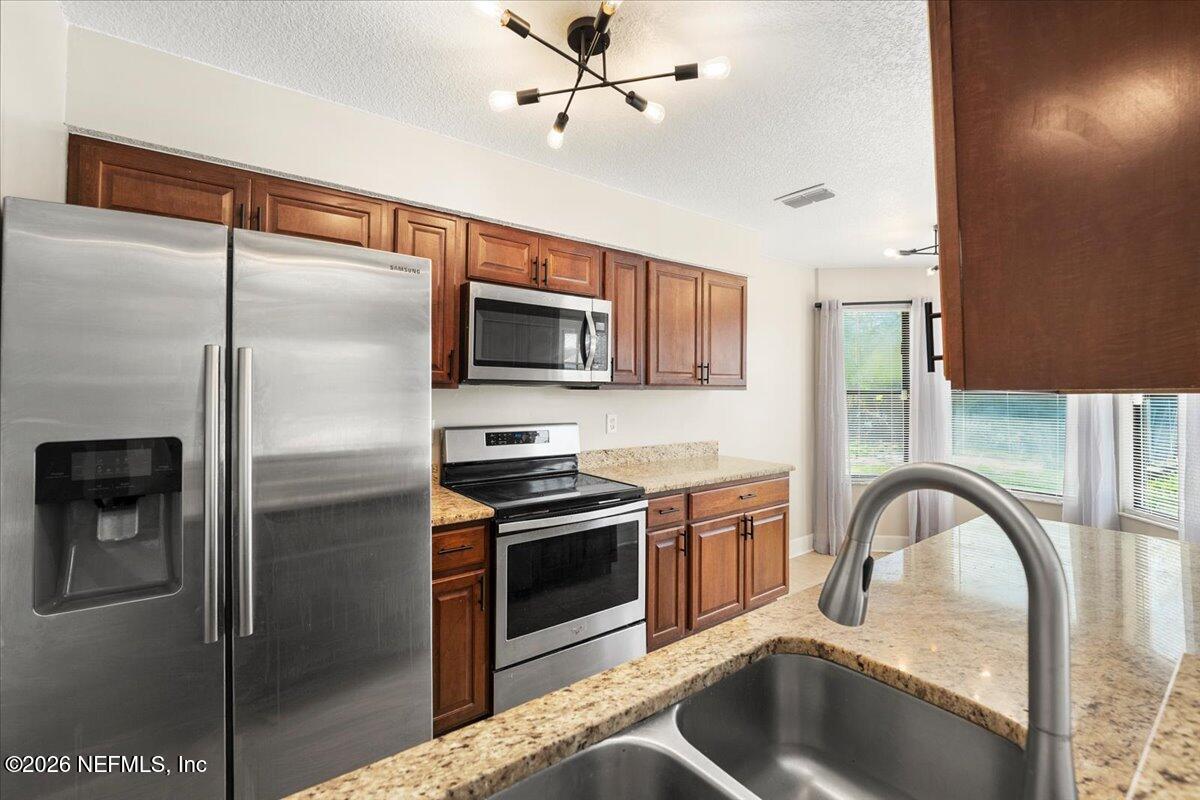 3255 Dowitcher Lane Orange Park, FL 32065 - Photo 7 of 39 a kitchen with stainless steel appliances granite countertop a refrigerator a stove a sink and dishwasher