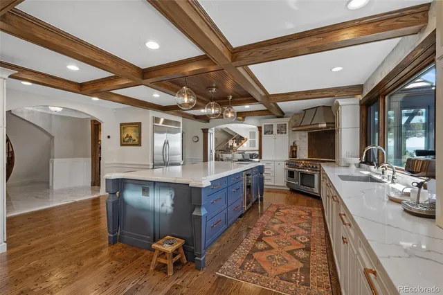 a large white kitchen with wooden floors and stainless steel appliances