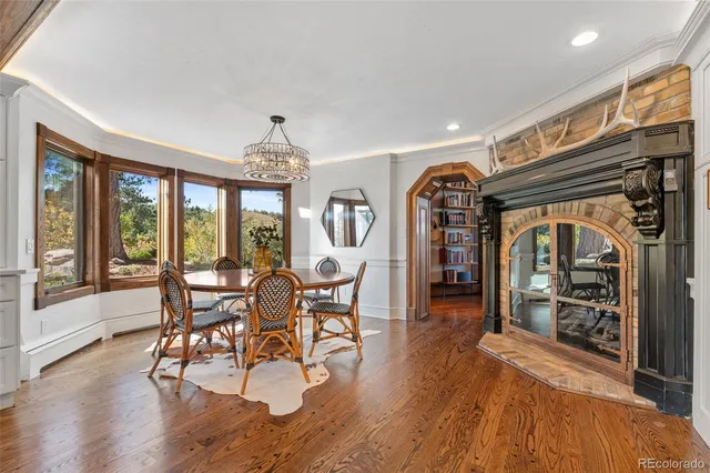 a dining room with wooden floor a chandelier a wooden table and chairs