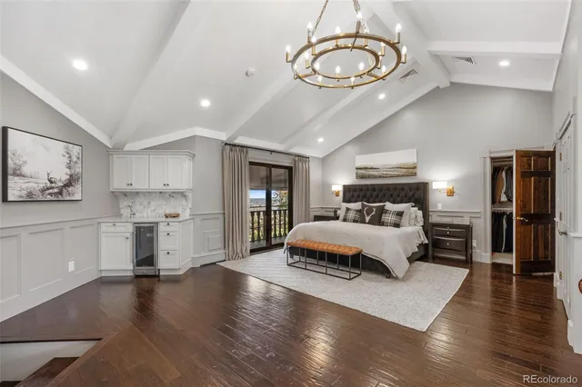 a bedroom with a bed a couch and large mirror with wooden floor