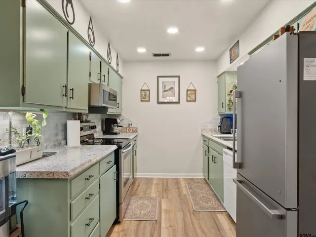 a kitchen with stainless steel appliances granite countertop a refrigerator and a sink