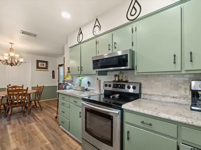 a kitchen with stainless steel appliances a stove a sink cabinets and a dining table