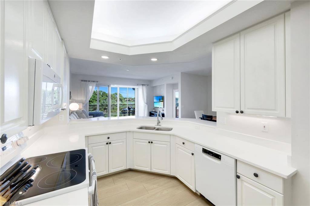 25161 Sandpiper Greens Court, Unit 203 Bonita Springs, FL 34134 - Photo 8 of 36 a kitchen with white cabinets and white appliances