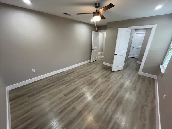 an empty room with wooden floor and a ceiling fan