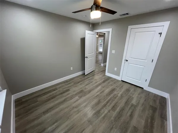an empty room with wooden floor closet and windows