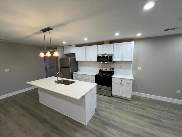 a kitchen with a sink stainless steel appliances and wooden floor