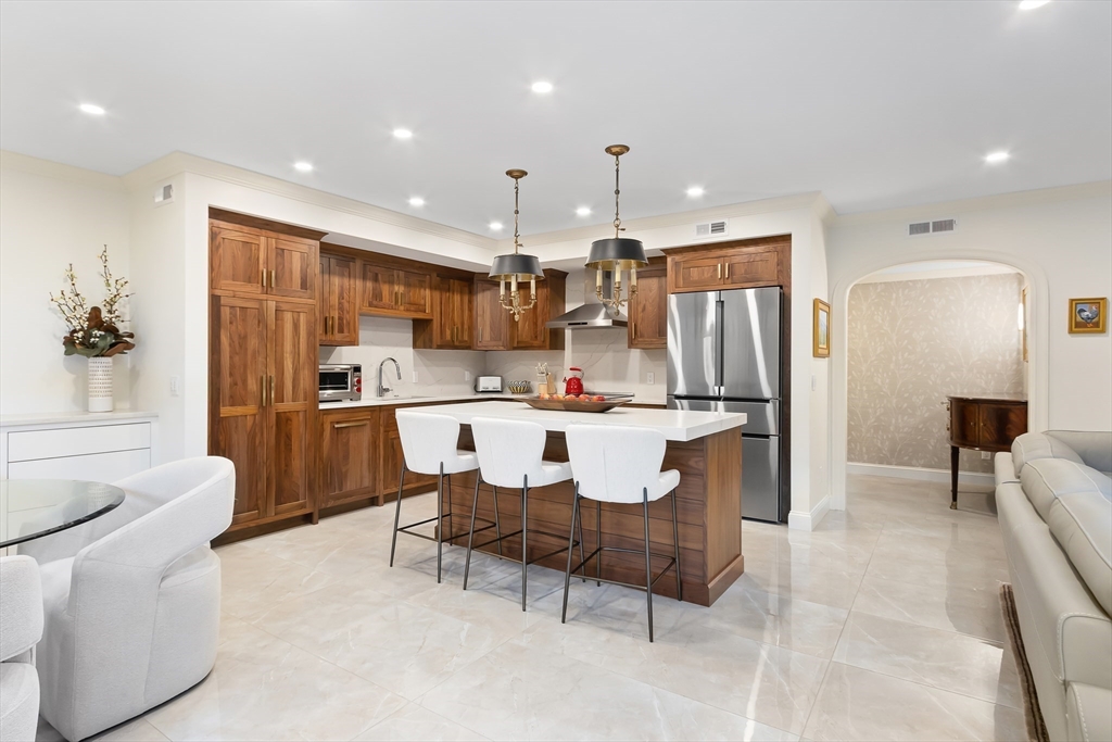 75 Grove Street, Unit 132 Wellesley, MA 02482 - Photo 6 of 20 a kitchen with kitchen island a refrigerator and a dining table