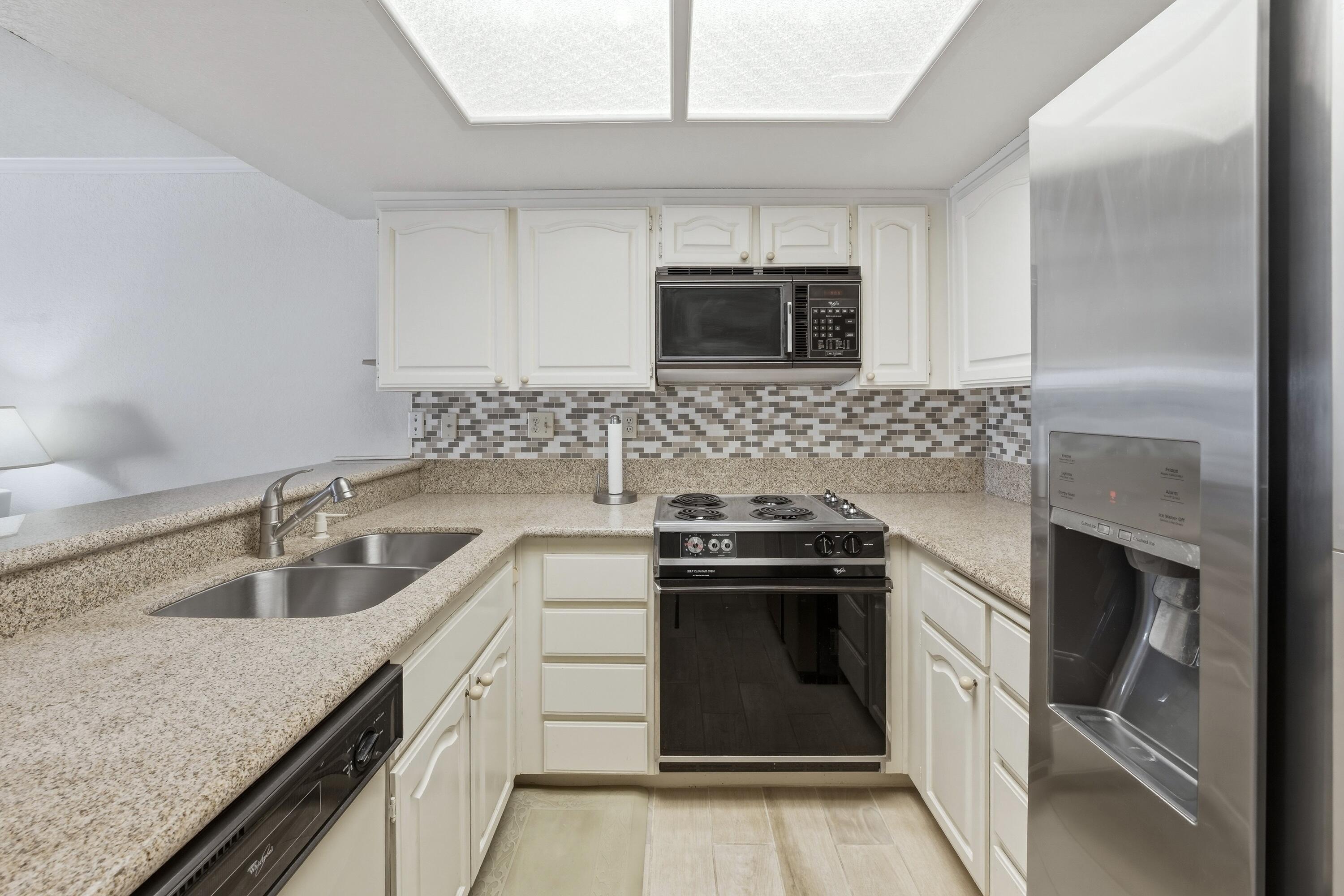 500 East Amado Road, Unit 511 Palm Springs, CA 92262 - Photo 17 of 28 a kitchen with granite countertop a stove sink and microwave