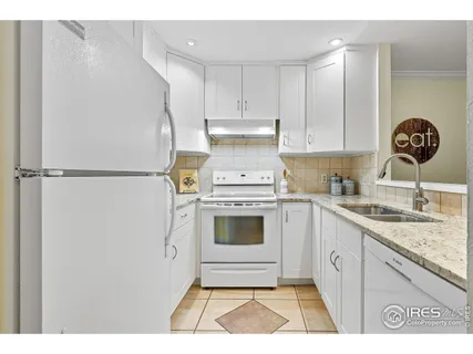 a kitchen with granite countertop white cabinets and white appliances