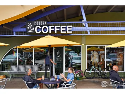 a view of a cafe with a table and chairs under an umbrella