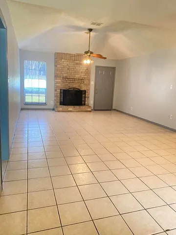 a view of an empty room with a fireplace and a window