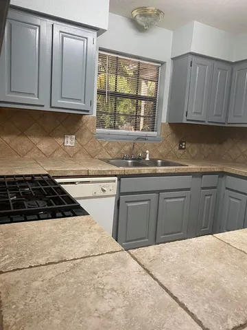 a kitchen with granite countertop white cabinets and appliances