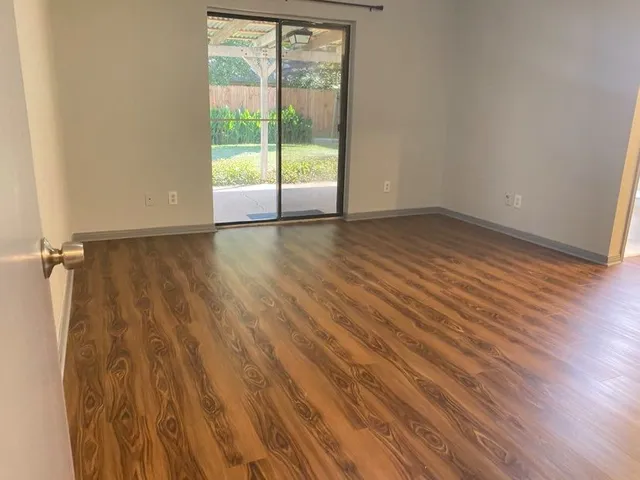 a view of an empty room with wooden floor and a window