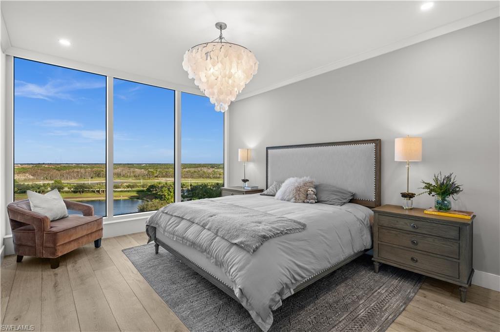 13925 Old Coast Road, Unit 1003 Naples, FL 34110 - Photo 19 of 33 Bedroom with a water view, light wood-type flooring, hanging lights, and crown molding