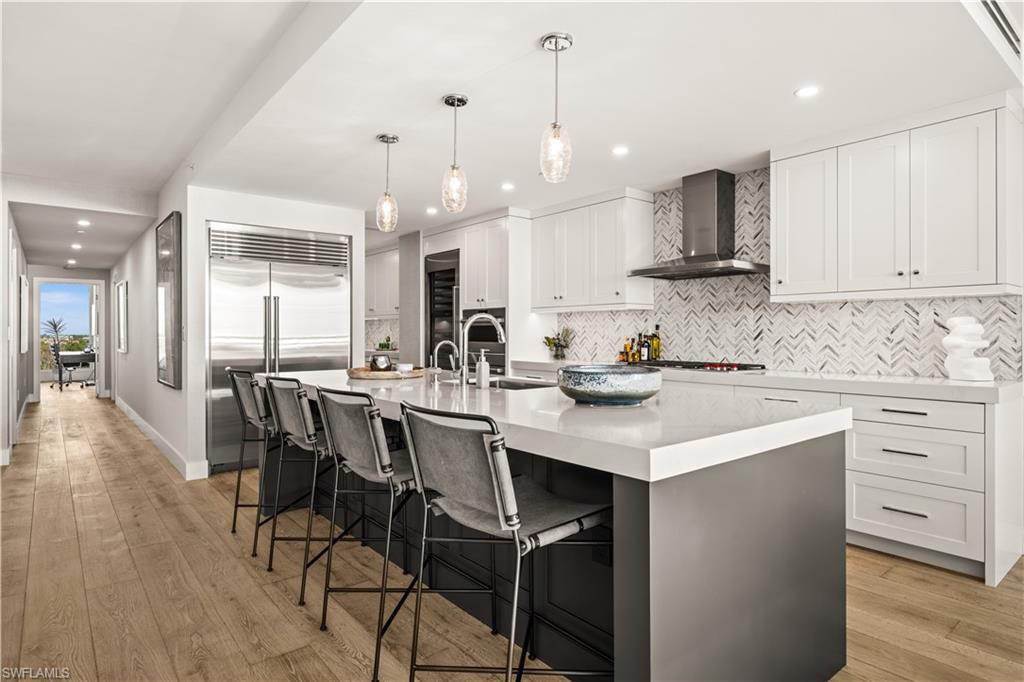 13925 Old Coast Road, Unit 1003 Naples, FL 34110 - Photo 9 of 33 Kitchen with a breakfast bar area, a spacious island, light wood-style floors, stainless steel appliances, and pendant lighting