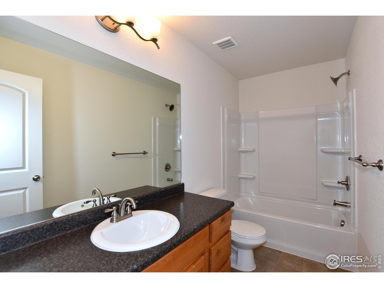 2304 Sublime Drive Windsor, CO 80550 - Photo 35 of 39 a bathroom with a granite countertop sink toilet a mirror and shower