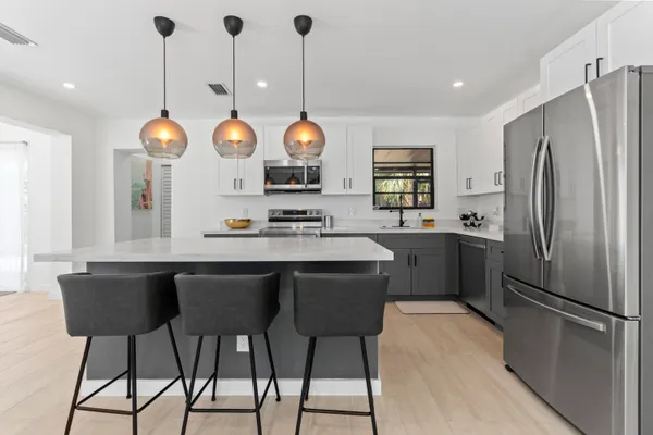 a kitchen with a refrigerator a sink and chairs