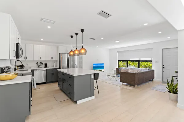 a kitchen with kitchen island stainless steel appliances a sink and a living room