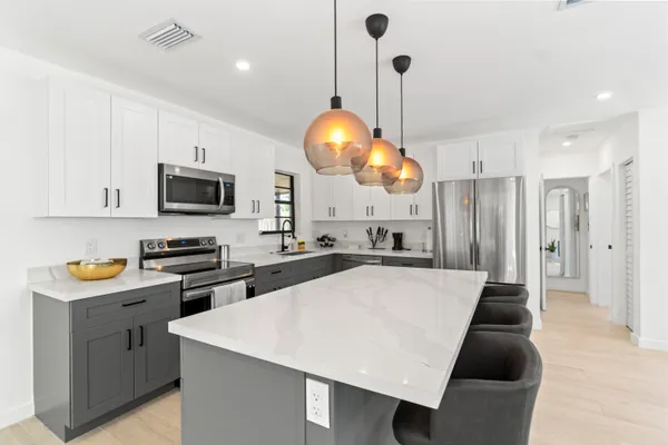 a kitchen with stainless steel appliances a stove a sink a microwave a dining table and chairs