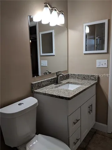 a bathroom with a granite countertop sink and a mirror
