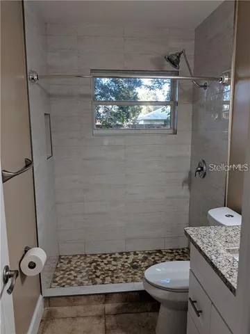 a bathroom with a granite countertop sink toilet and shower