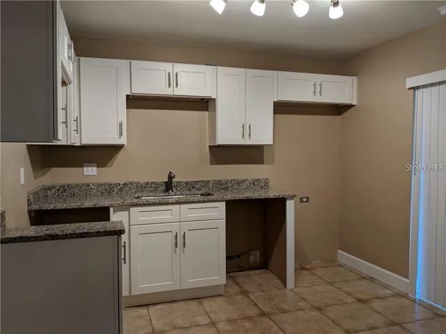 a kitchen with granite countertop cabinets sink and stove