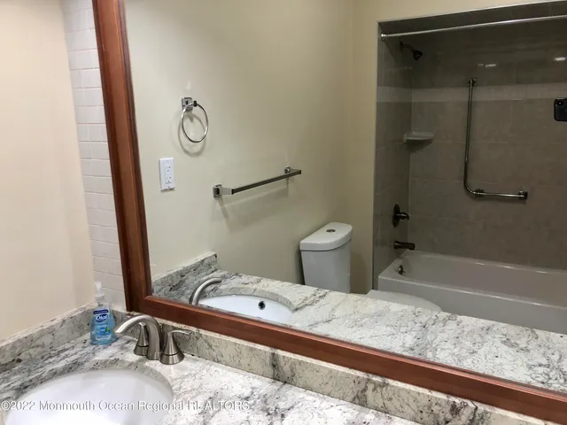 a bathroom with a granite countertop sink toilet and shower