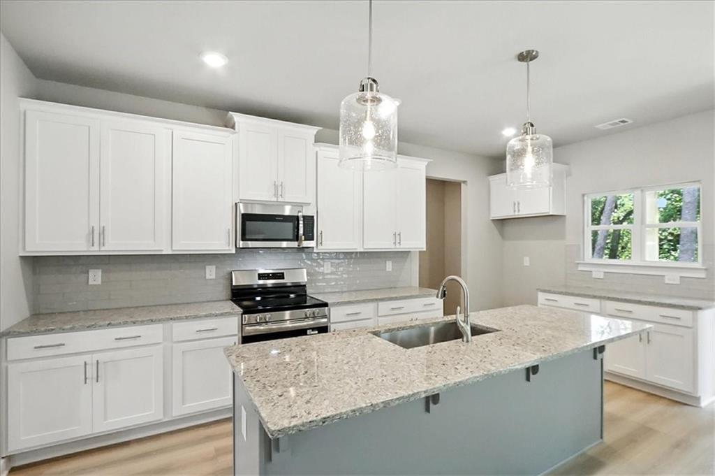 4034 Links Boulevard Jefferson, GA 30549 - Photo 16 of 68 a kitchen with granite countertop a sink stainless steel appliances and white cabinets
