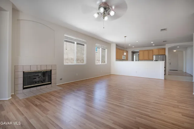 an empty room with wooden floor fireplace and a window