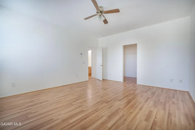 a view of empty room with wooden floor and fan