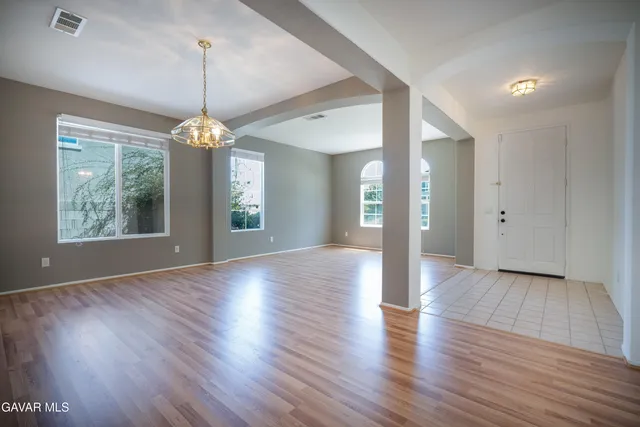 a view of an empty room with wooden floor and a chandelier