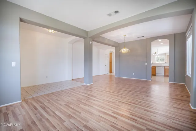 a view of an empty room with wooden floor and a bathroom