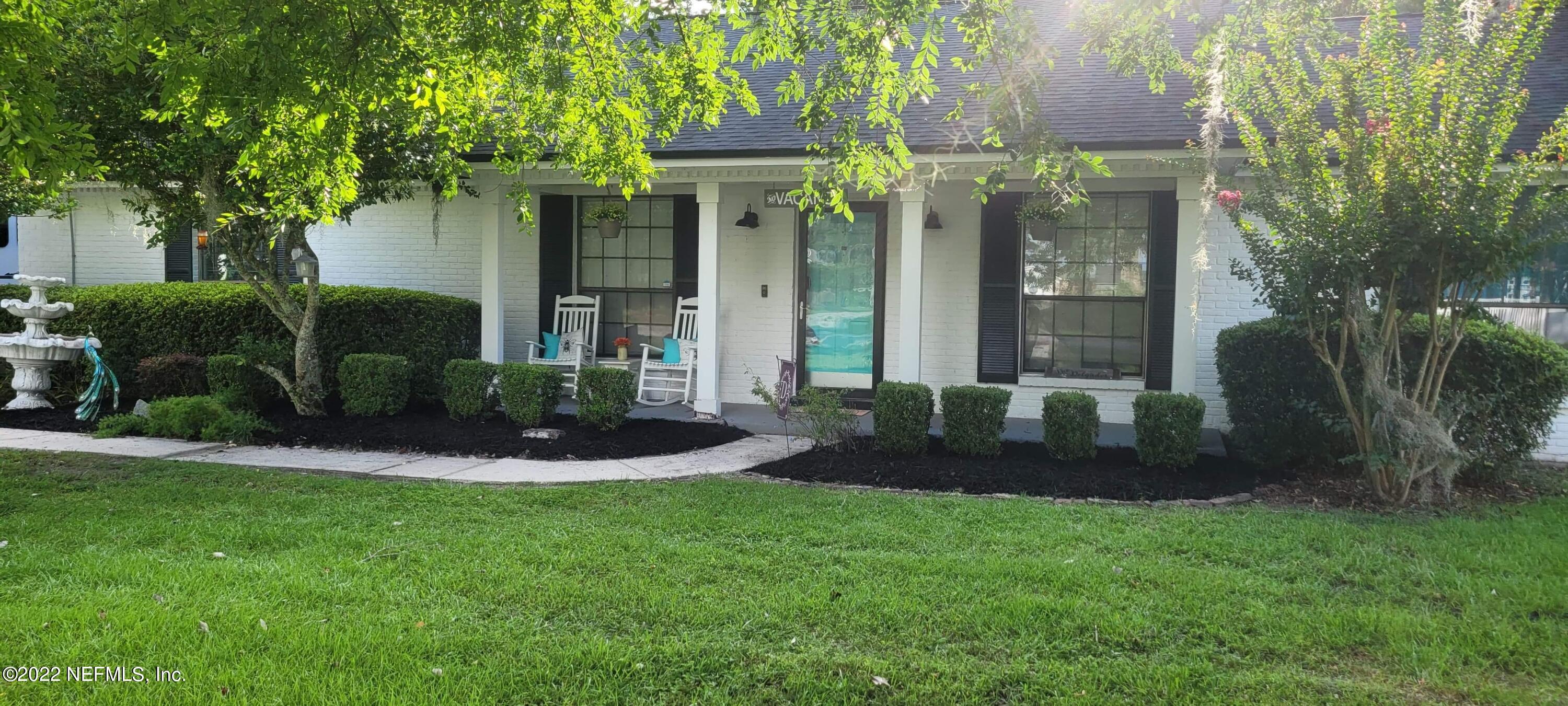 6044 West Shores Road Fleming Island, FL 32003 - Photo 2 of 18 a view of a brick house with a yard and large trees