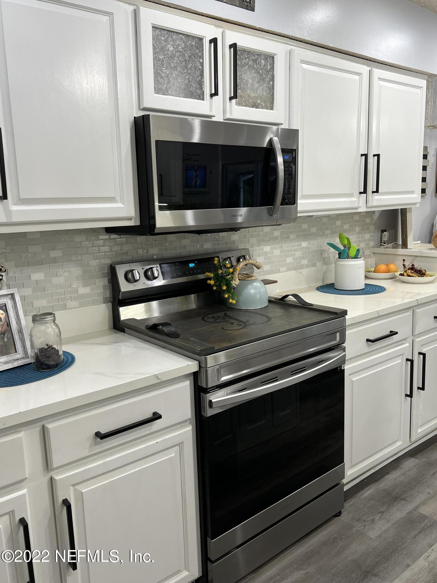 6044 West Shores Road Fleming Island, FL 32003 - Photo 8 of 18 a kitchen with stainless steel appliances a stove microwave and cabinets