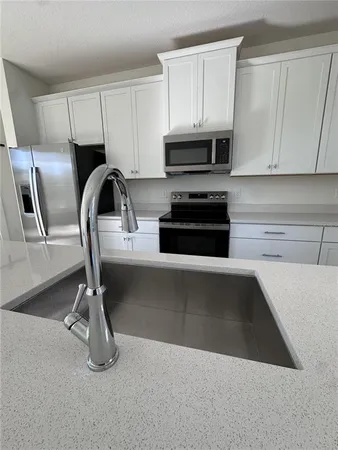 a kitchen with granite countertop white cabinets and stainless steel appliances