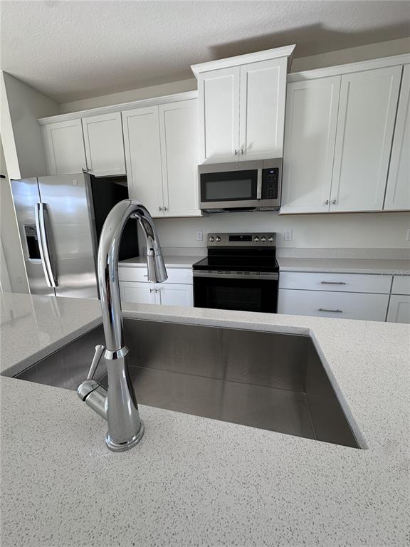 2059 Iorio Street St. Cloud, FL 34771 - Photo 15 of 61 a kitchen with stainless steel appliances a stove a sink a microwave and cabinets