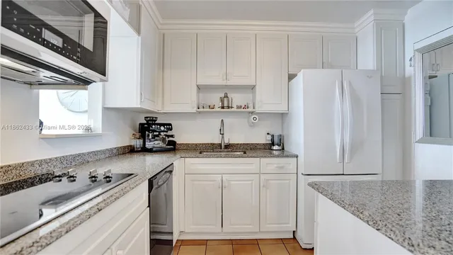 a kitchen with granite countertop white cabinets and white appliances
