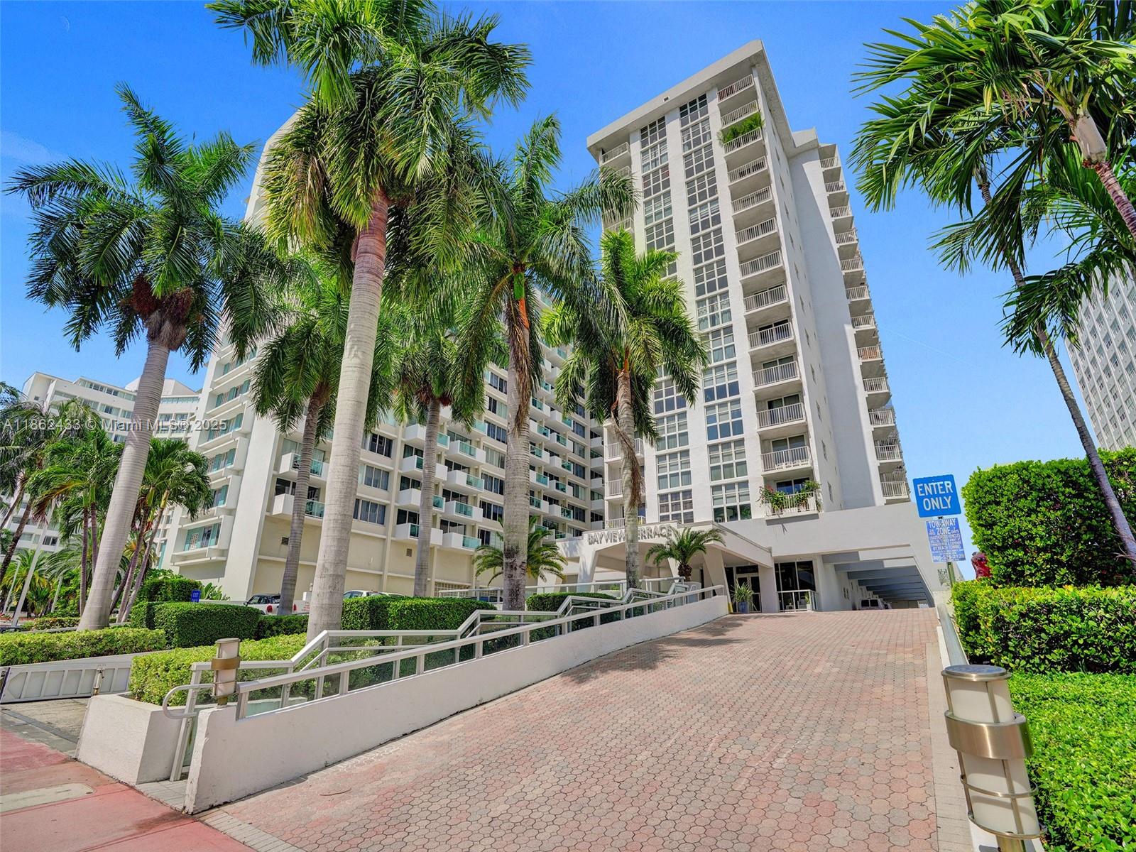 1228 West Avenue, Unit 201 Miami Beach, FL 33139 - Photo 34 of 42 a front view of a residential apartment building with a yard and palm trees