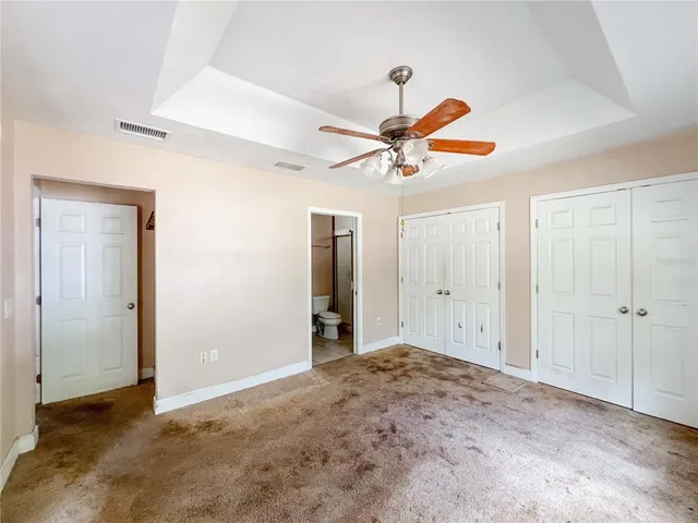 an empty room to closet and a ceiling fan