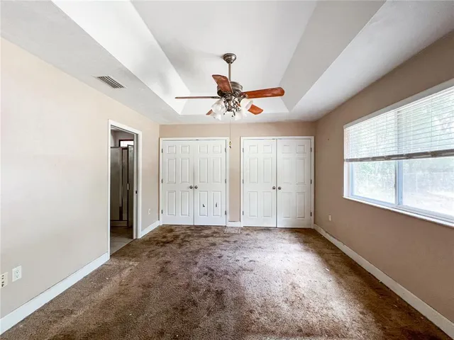 a view of a livingroom with a chandelier fan and windows